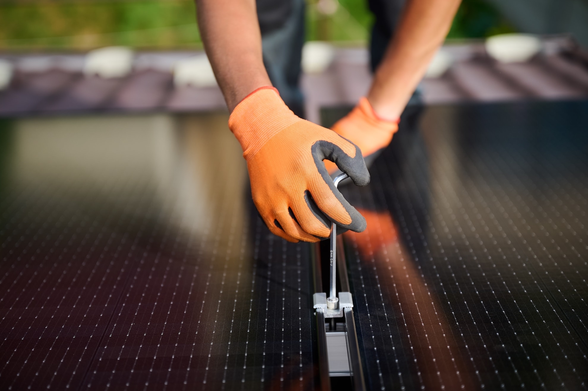 Worker building photovoltaic solar panel system on rooftop of house.