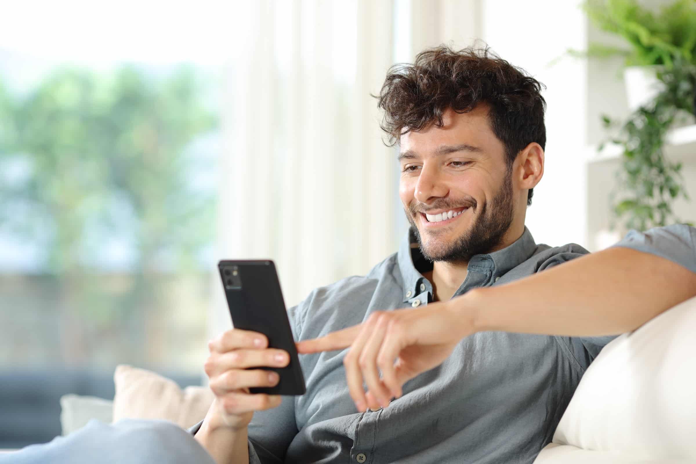 Happy man using phone at home
